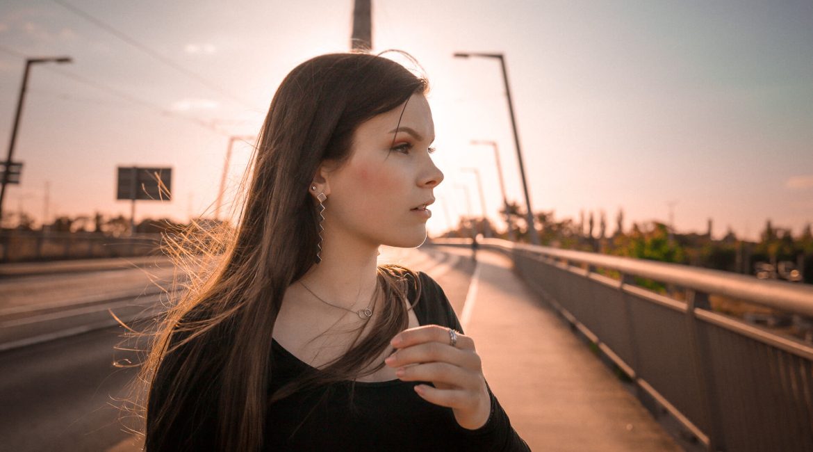Portraitfoto von junger Frau auf Brücke im Sonnenuntergang in Halle
